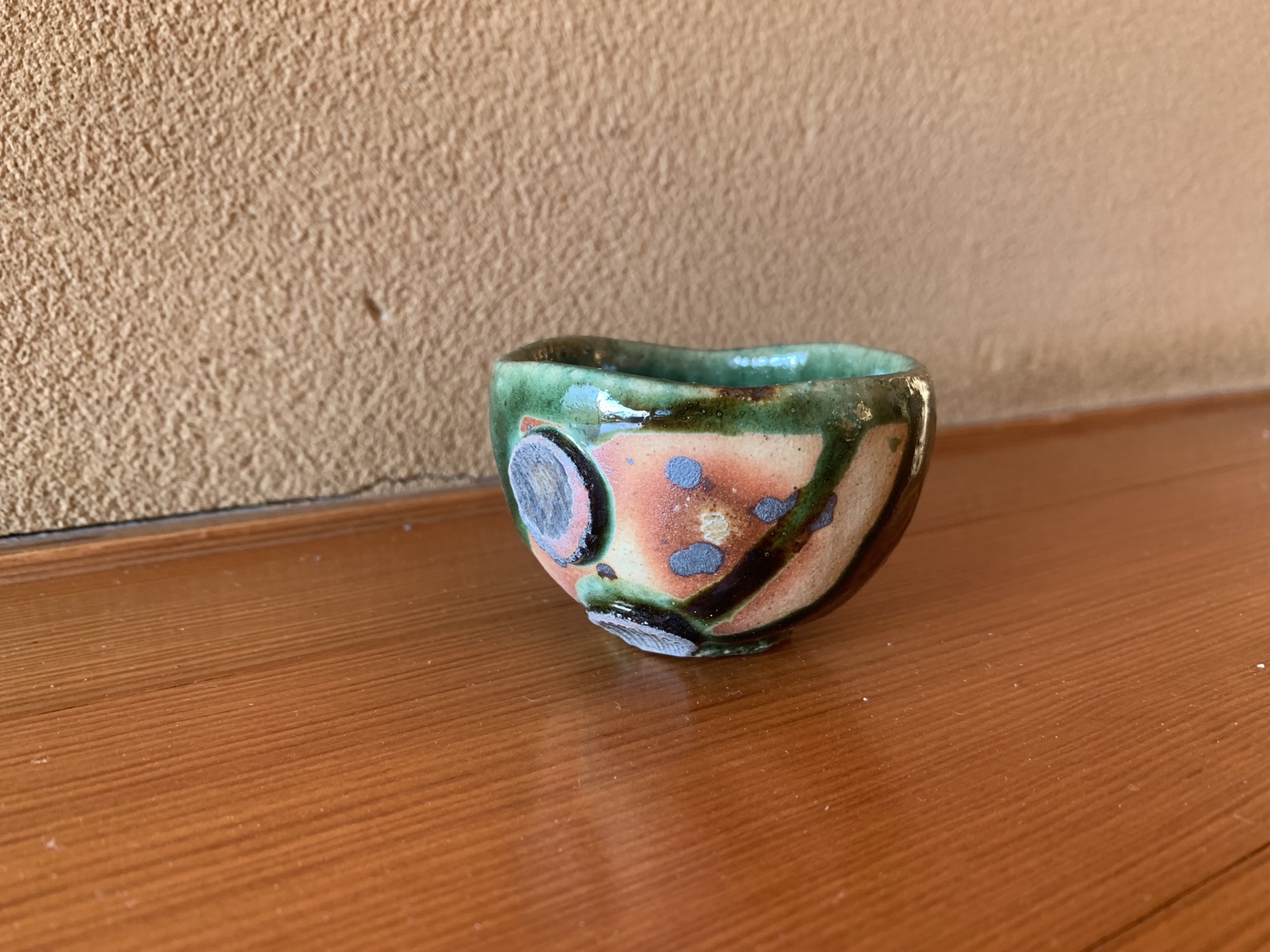 赤みのある土肌に緑の釉薬と丸い模様を配したうつわ