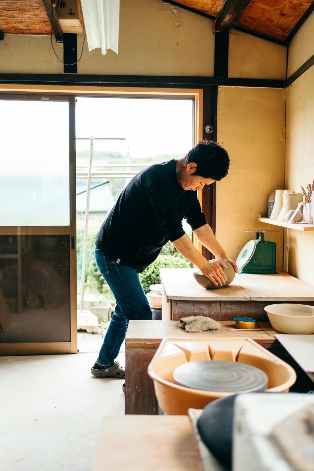 工房の作業台で、両手で土を練る加藤裕